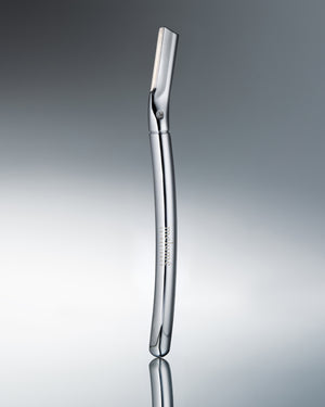 A polished stainless steel electric razor standing vertically on a reflective gray surface against a gradient gray background.